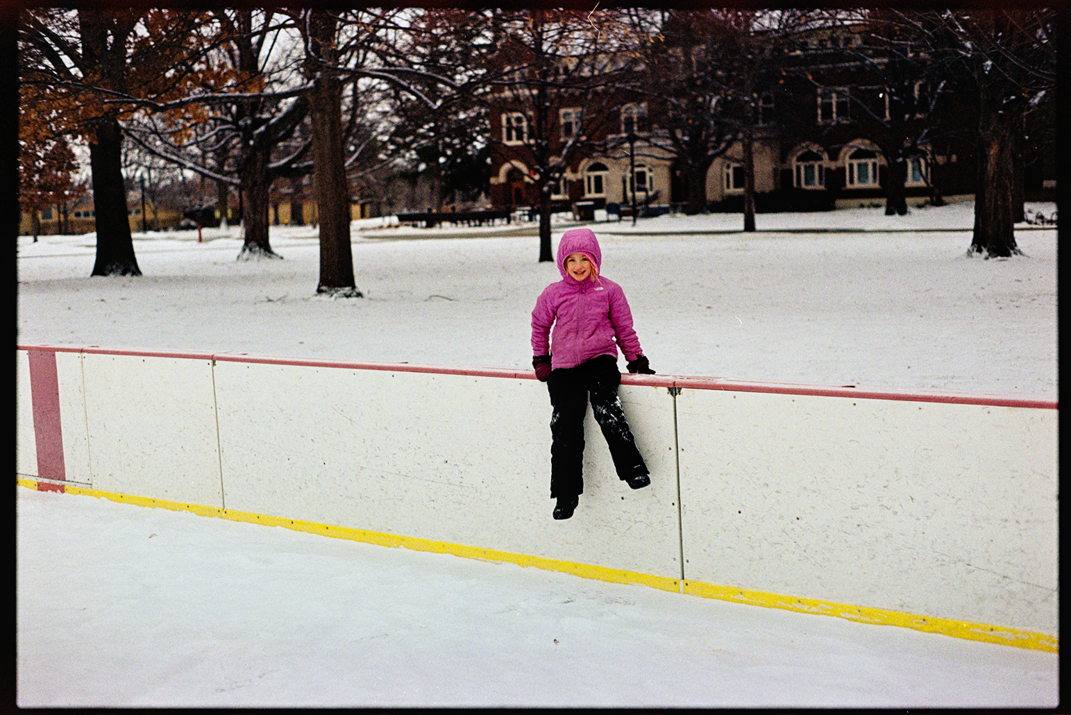 Anna the young girl wearing a pink snow jacket outside in an ice rink