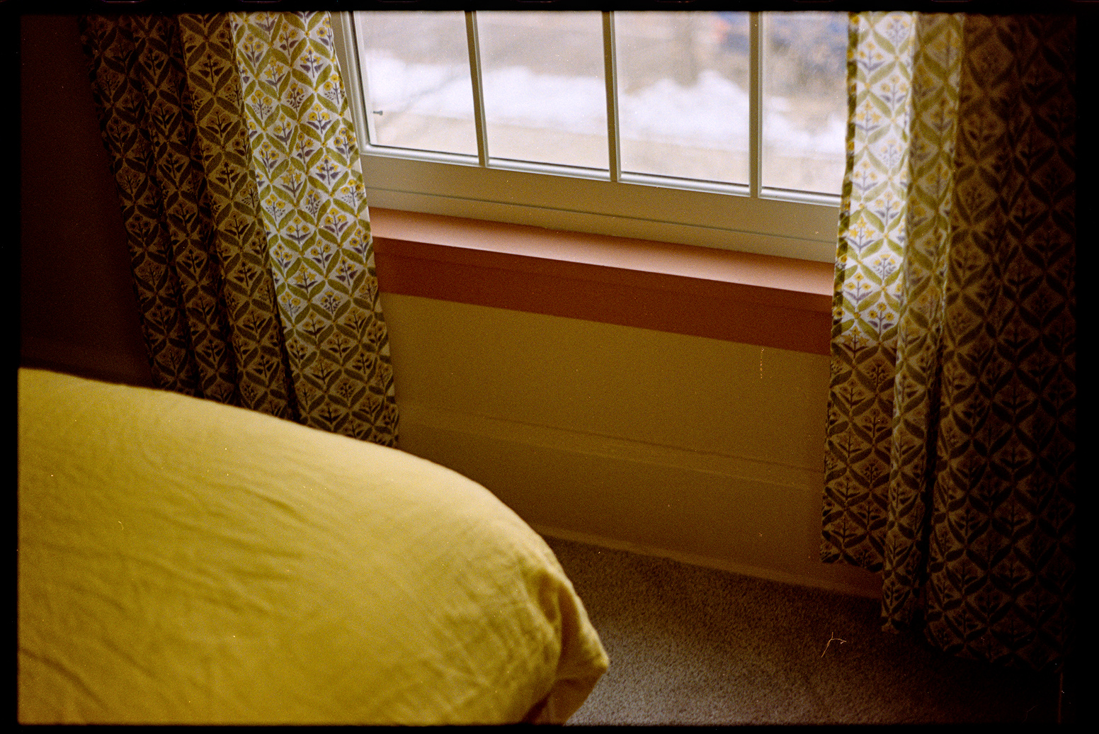 Bed with a yellow duvet near a window with green curtains