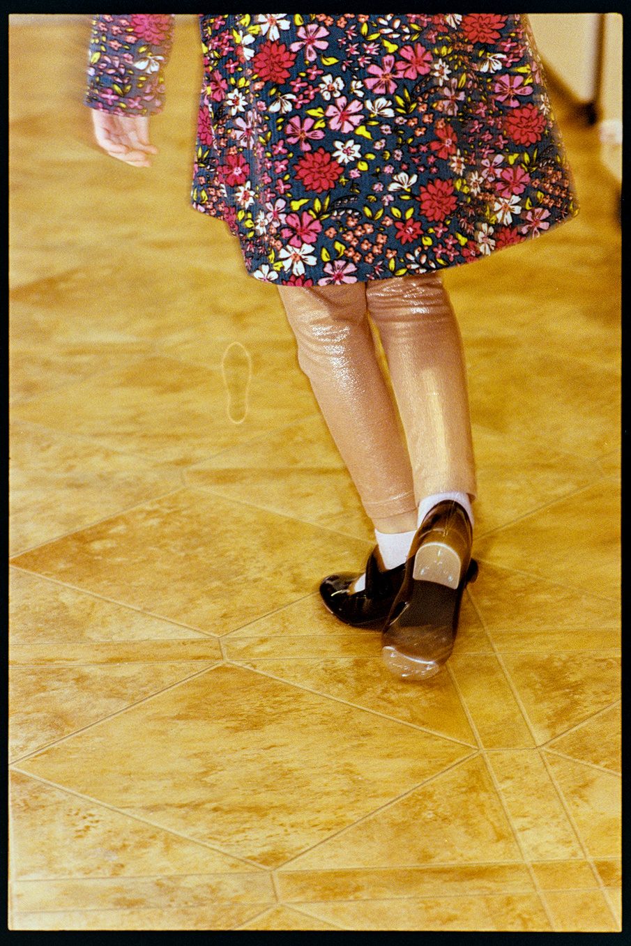 Lena, a young girl, shot from the waiste down as she dances in tap shoes