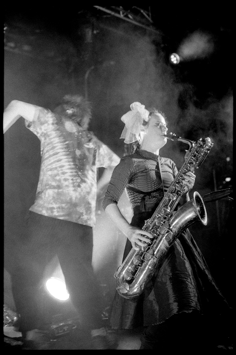Kalmia playing baritone saxophone while Alex dances behind her in a Rubblebucket concert in St. Paul