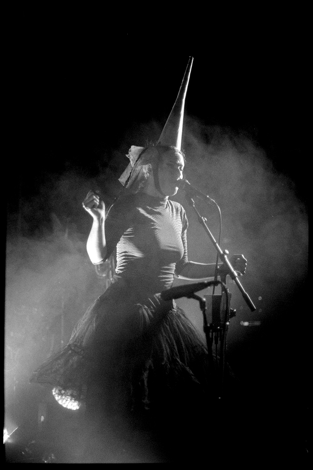 Kalmia singing in the spotlight while wearing a tall pointy hat in Rubblebucket concert in St. Paul