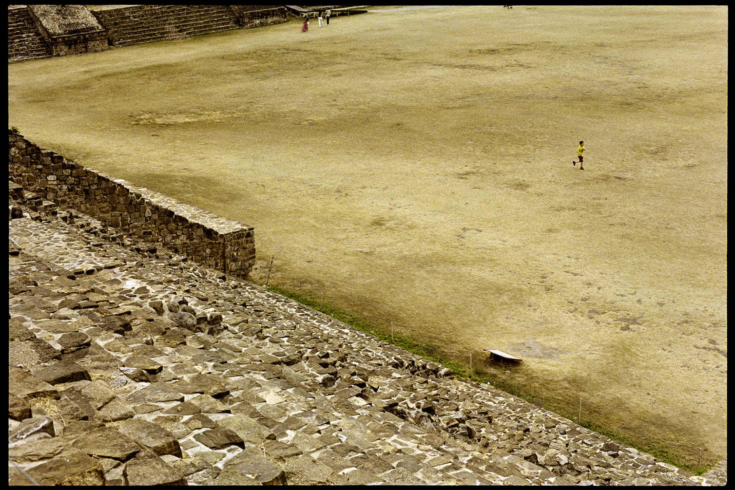 Boy running through expanse of yellow grass at Monte Alban in Oaxaca City
