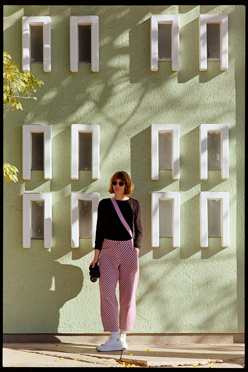 Kallie in front of a green wall in contrasty sun in Oaxaca City