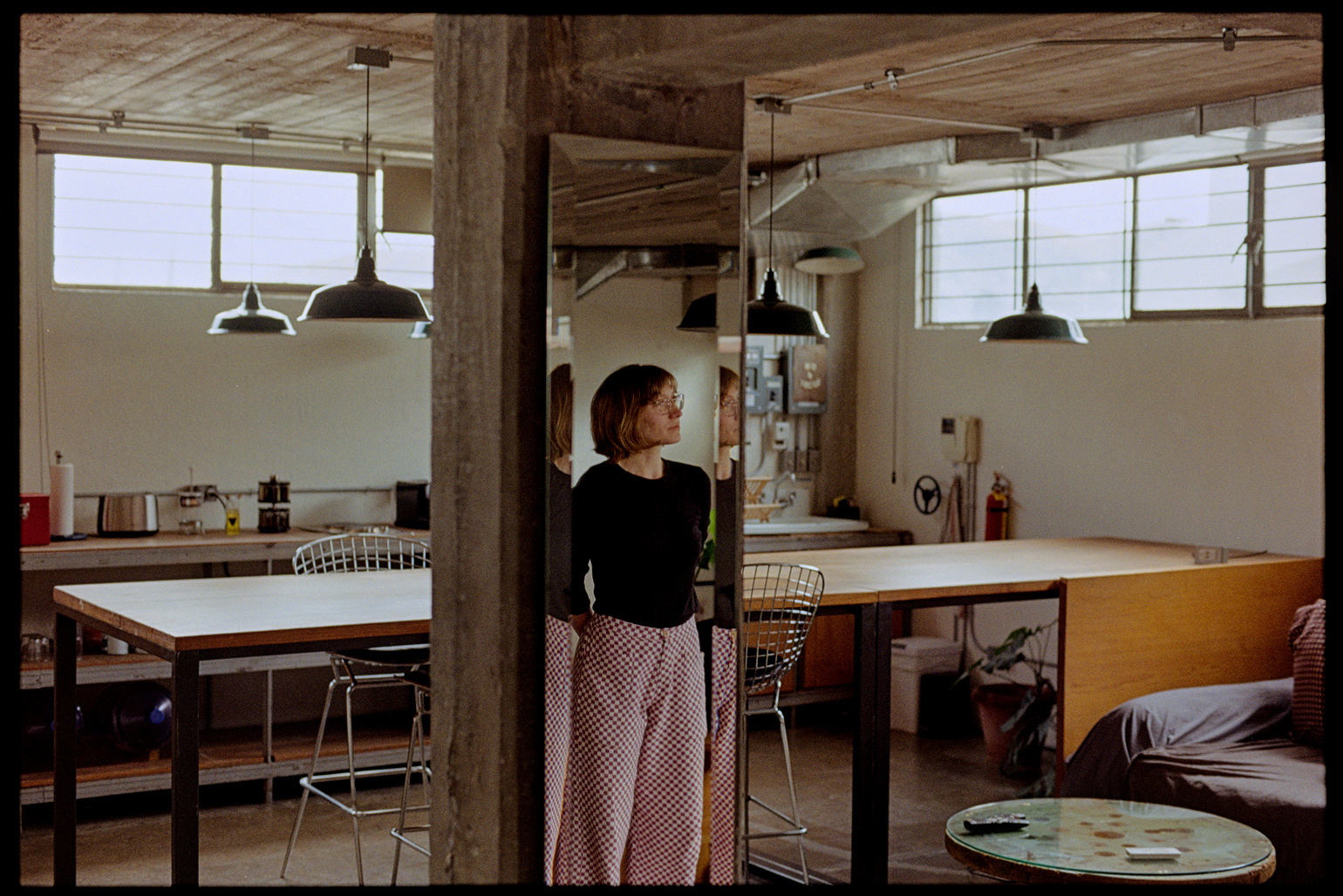 Kallie reflected in a mirror in a concrete minimalist apartment in Oaxaca City