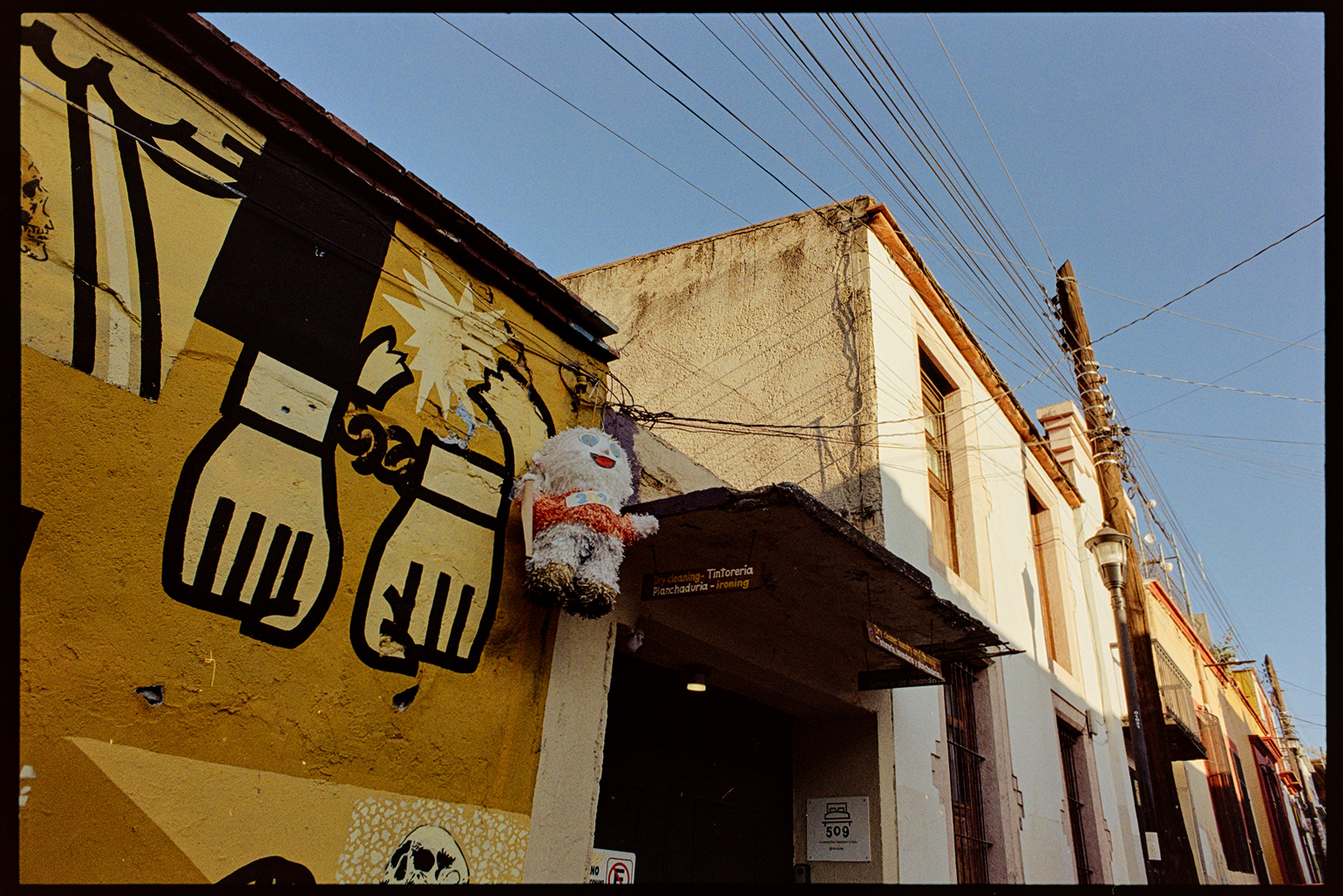 A pinata of a person hanging off the roof of a building in Oaxaca City
