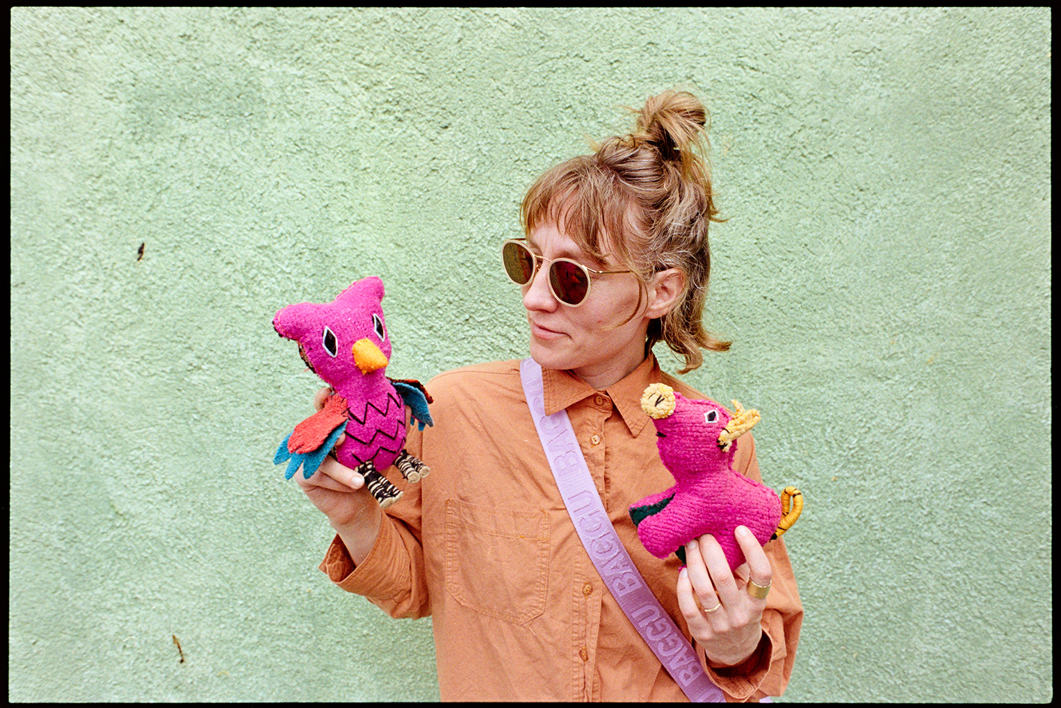 Kallie standing against a green wall holding two pink stuffed animals in Oaxaca City