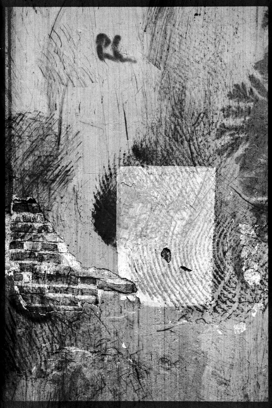 Wall of a building with plaster, exposed brick, and patch of white paint in Oaxaca City