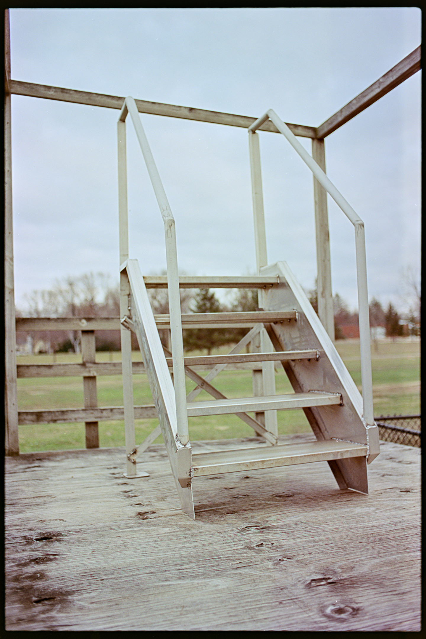 A metal podium with stairs that overlooks an empty field