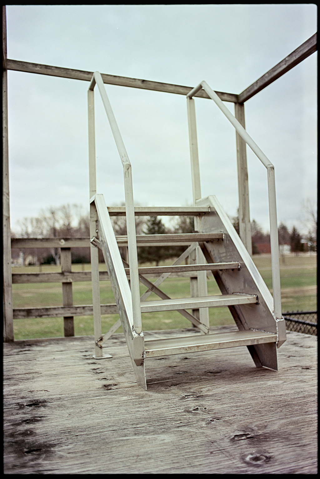 A metal podium with stairs that overlooks an empty field