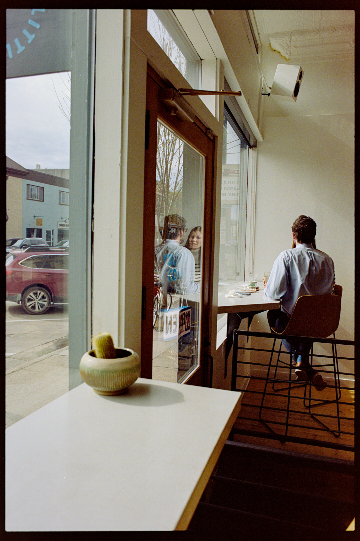 Two people sitting in the front window of Little Joy coffee shop
