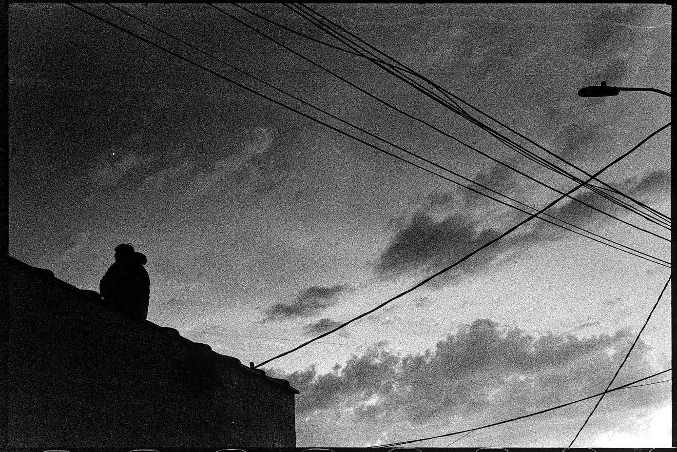Man sweeps the roof of his business facing the sunset after a storm