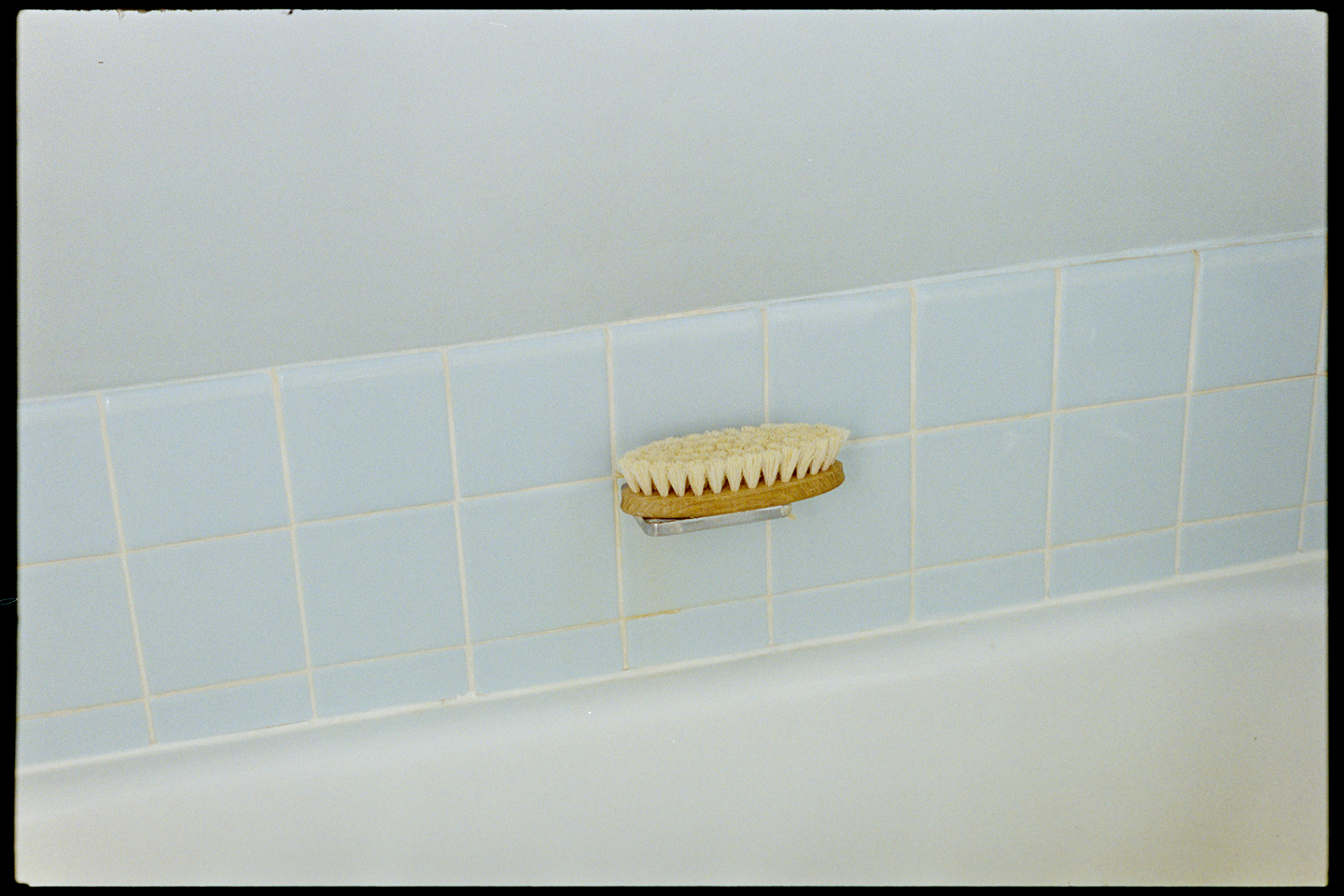 A wooden brush on a baby blue bathtub