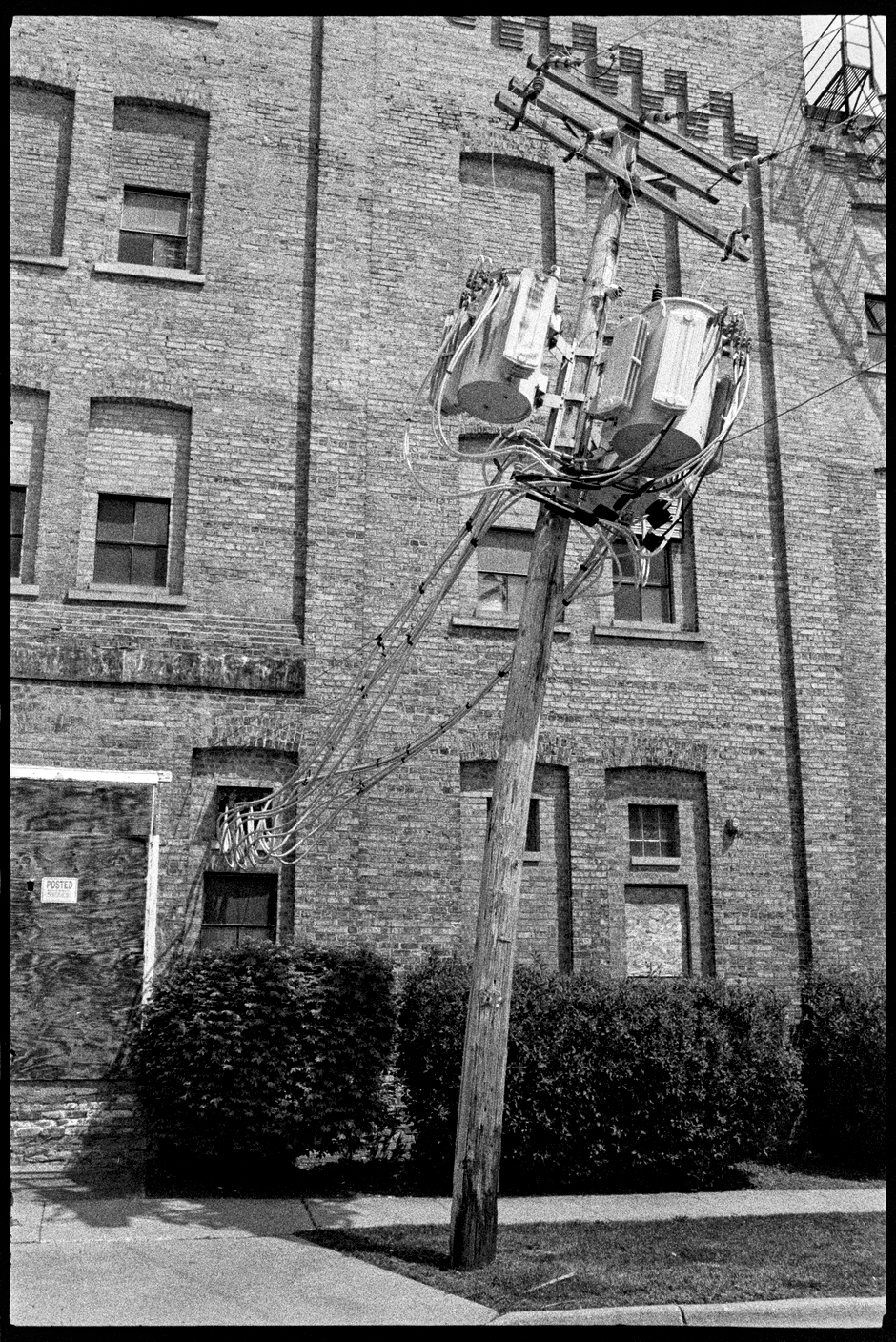 Old brick building with a slanted electrical pole in front