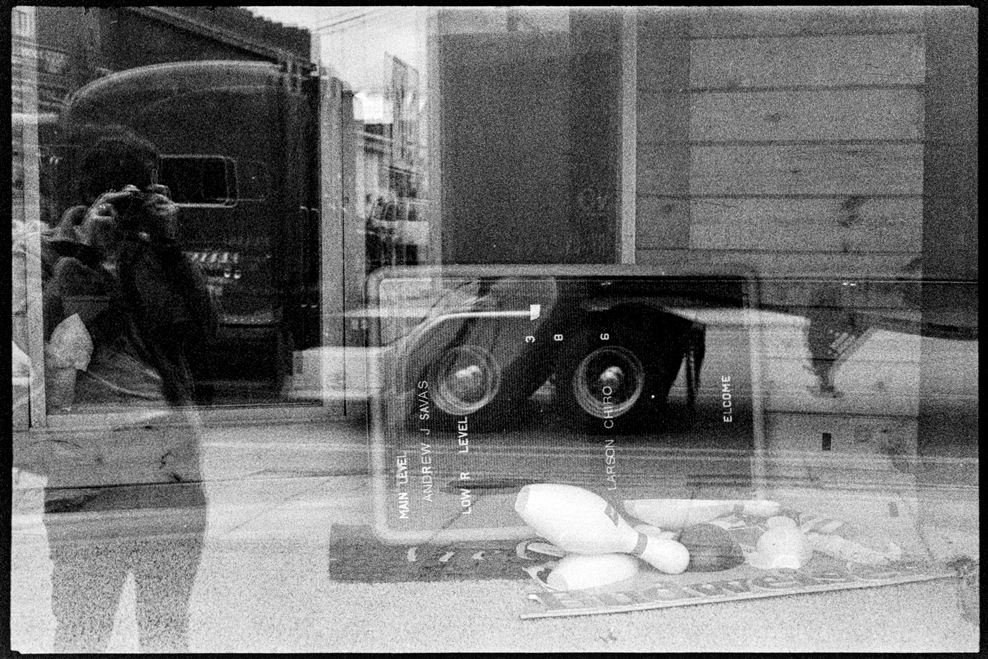 Jason and a passing semi truck in the reflection off the window of a bowling alley