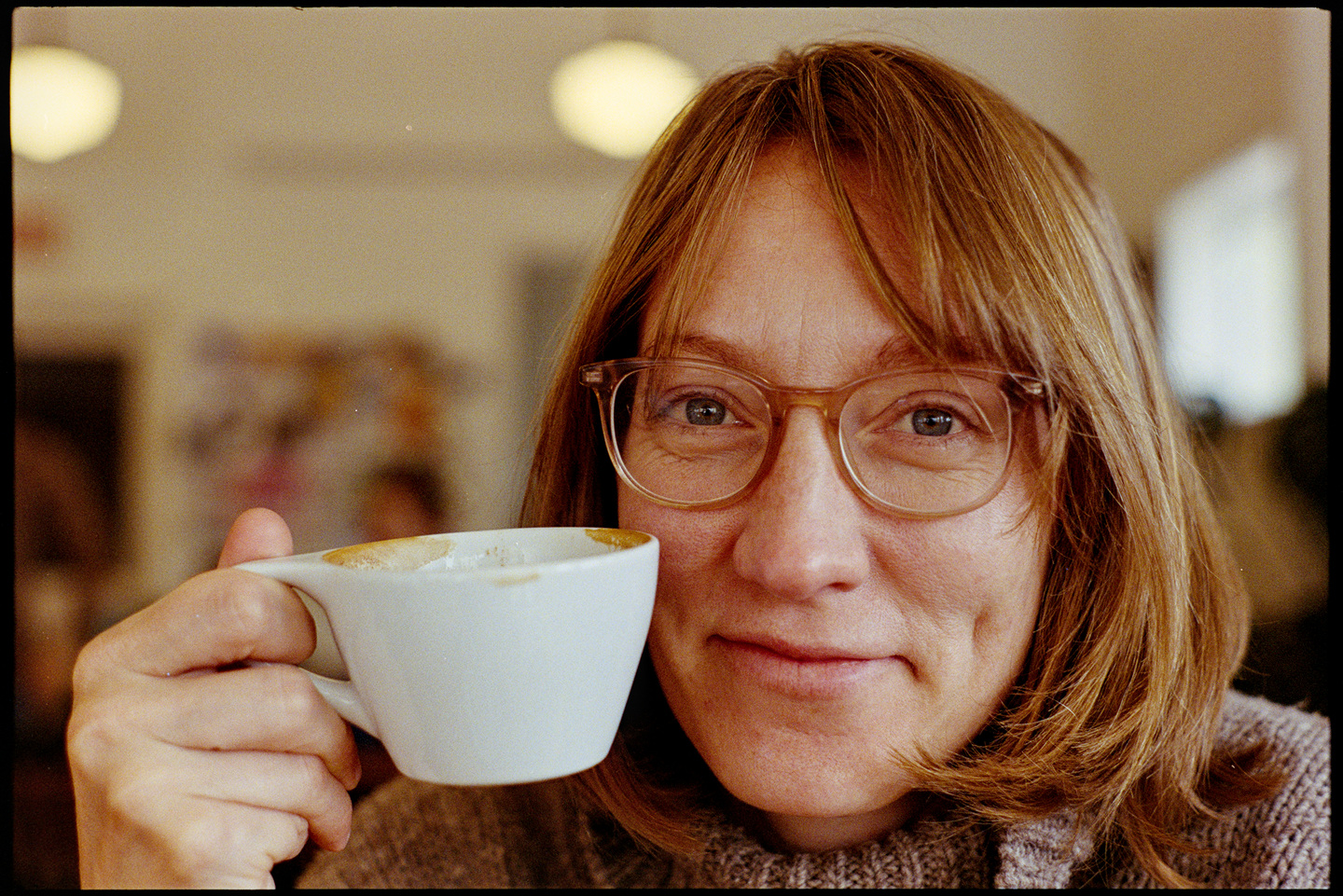 Kallie holding a white mug up to her face at Wonder State Coffee in Bayfield, Wisconsin