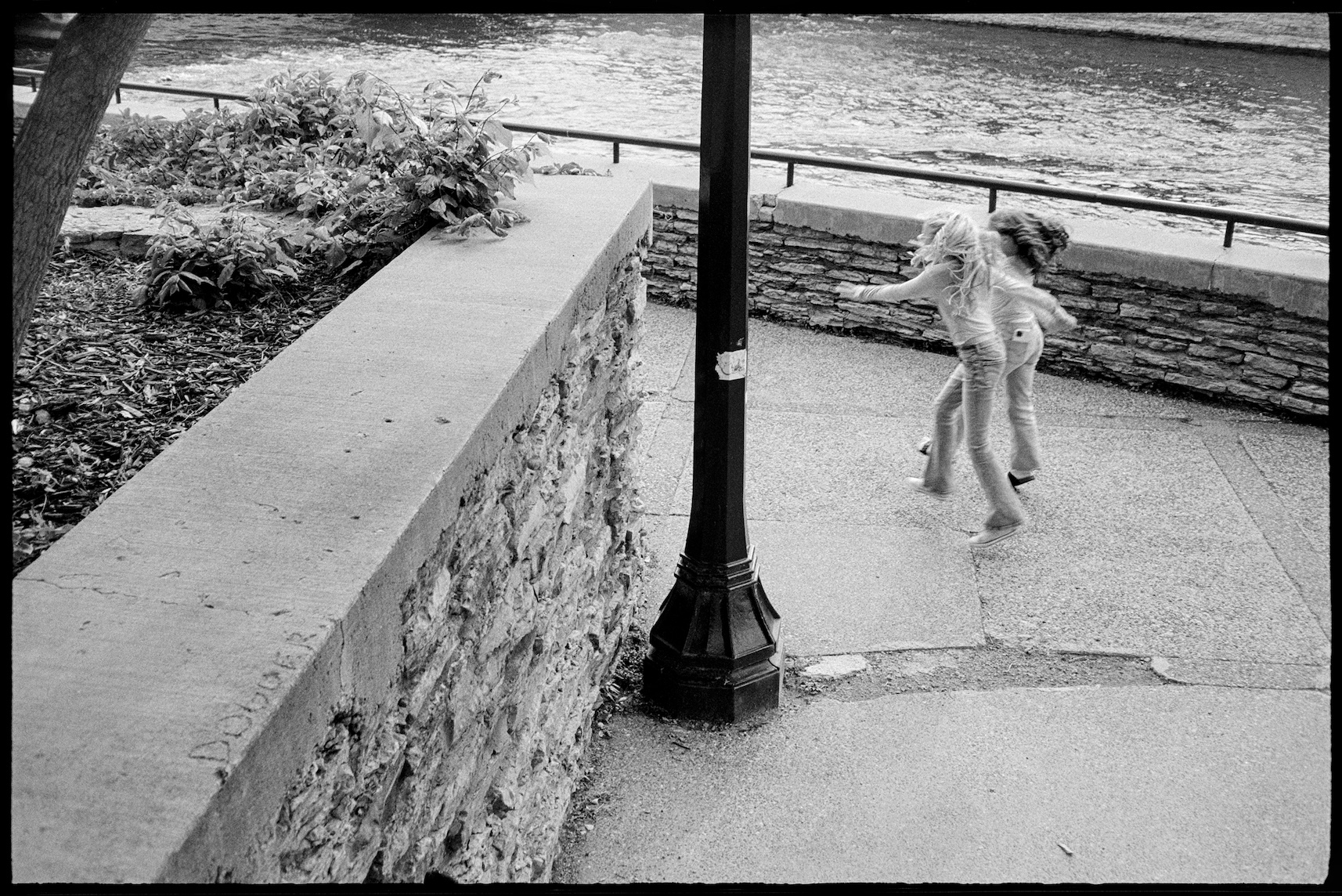 Two young girls skipping together along the riverwalk