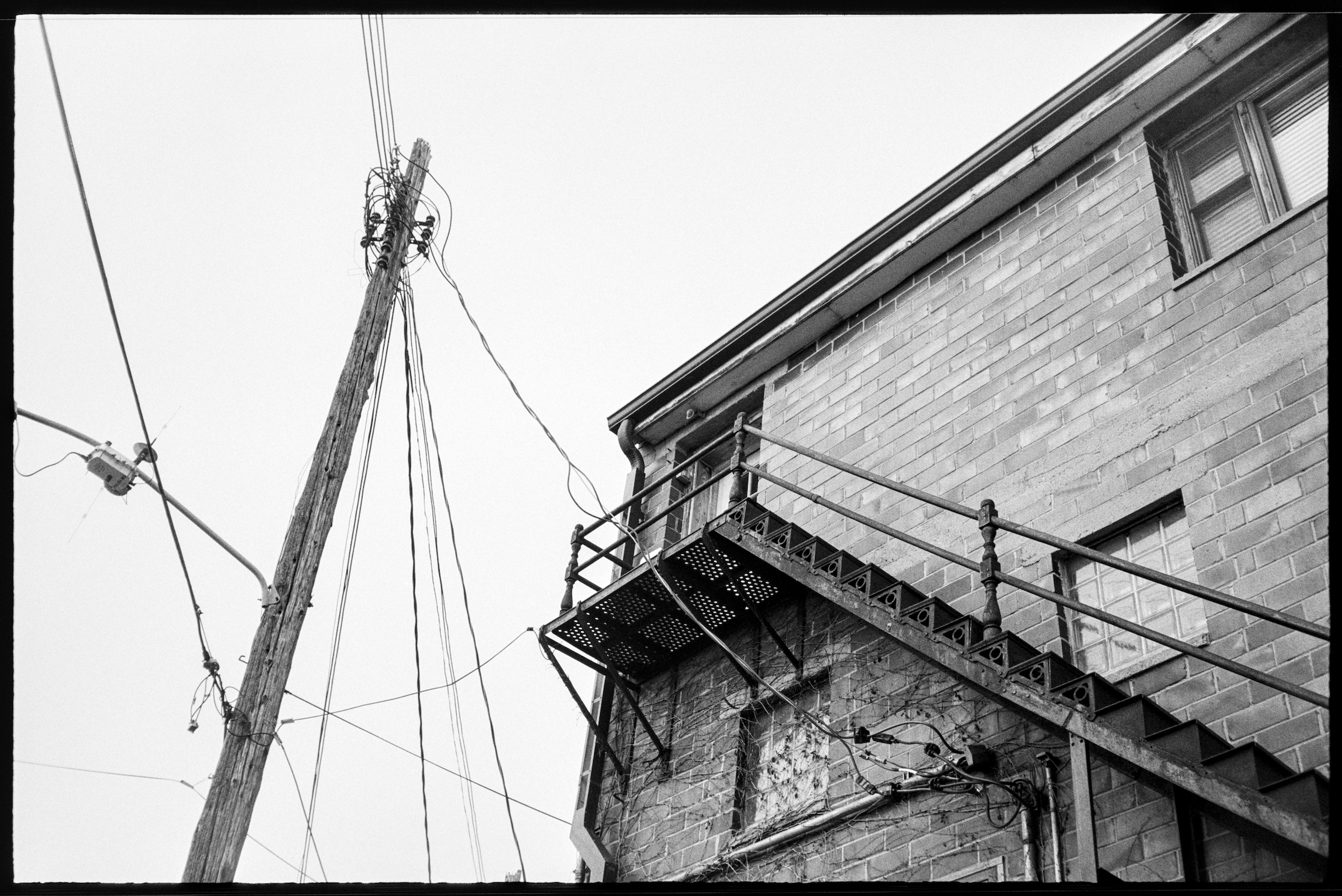 Old brick apartment building with fire escape and a telephone pole
