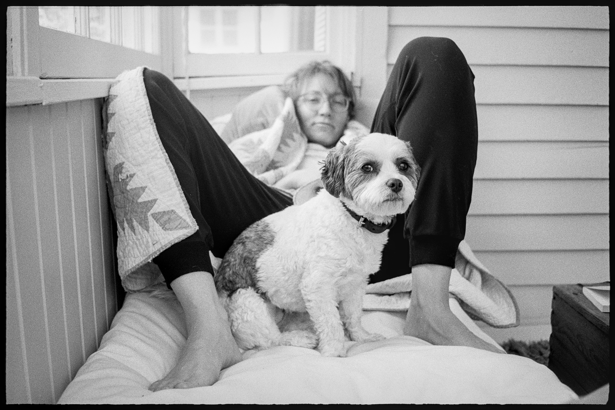 Annie sitting between Kallie's legs on the porch