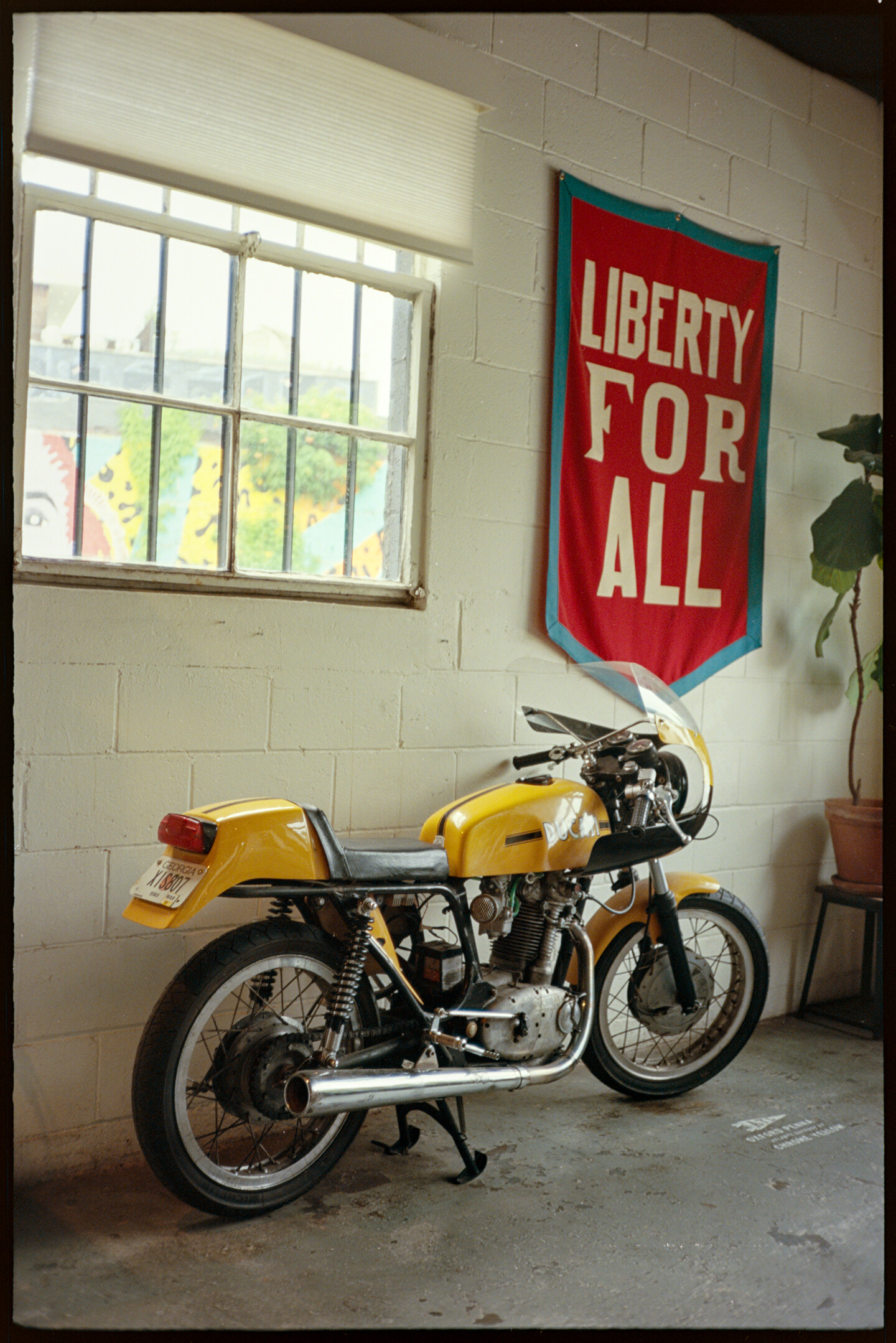 Yellow Ducati motorcycle under a Liberty for All banner inside the Chrome Yellow coffee shop in Atlanta