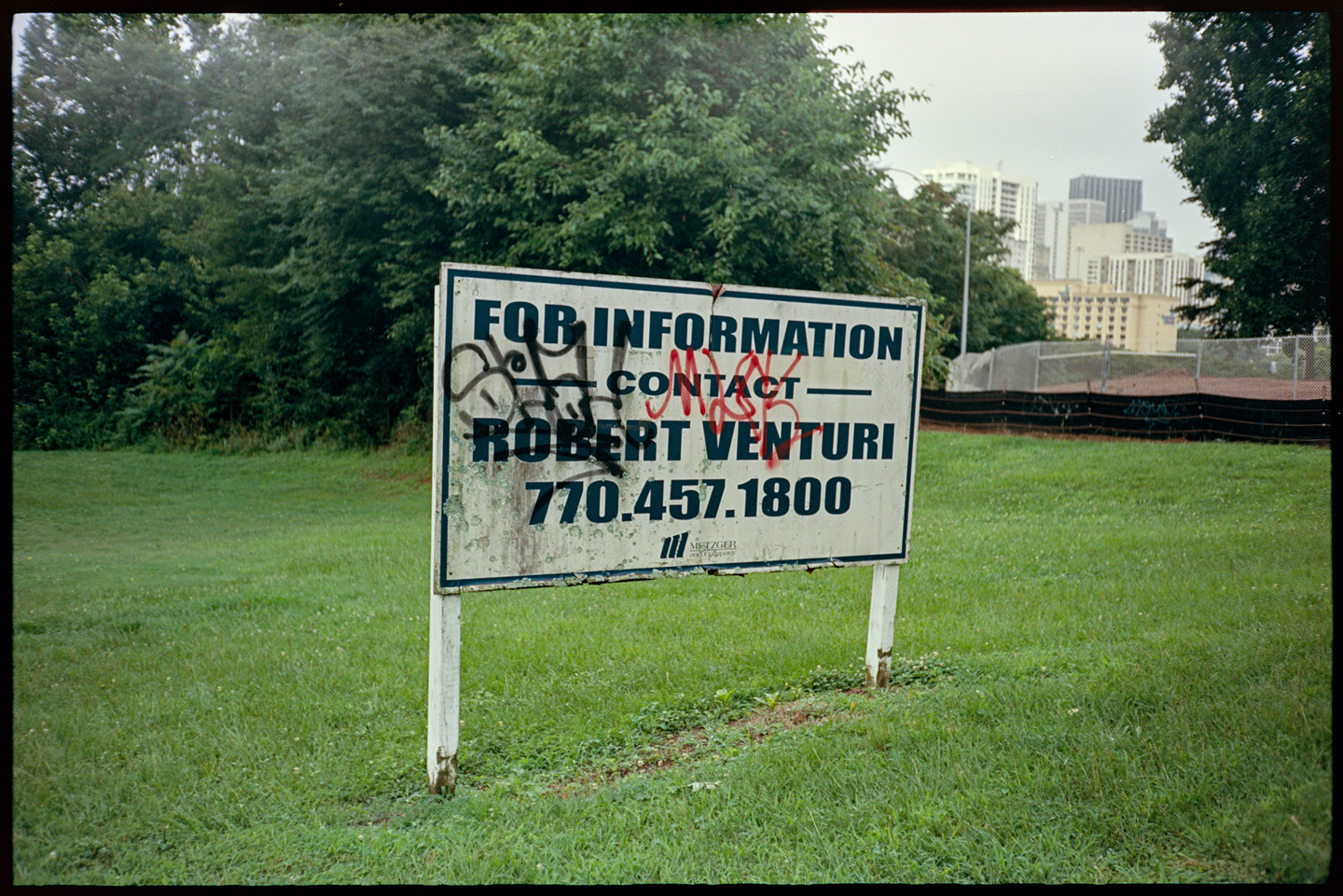 A sign on an empty lot of grass in Atlanta that says For information contact Robert Venturi 770-457-1800