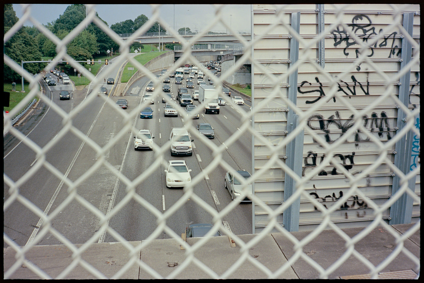 A busy highway cutting through Atlanta, shot on an overpass through a chain link fence