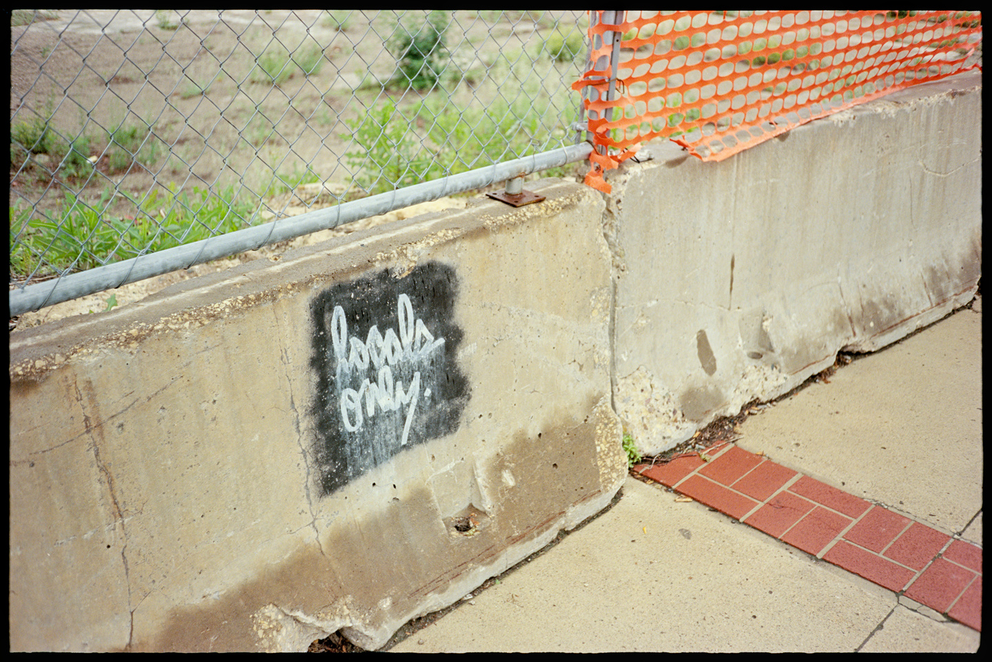 Concrete barriers surrounding a construction zone, one with graffiti that says Locals Only on it
