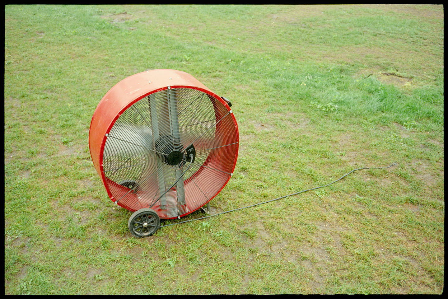 A large circular red fan spinning in a green field