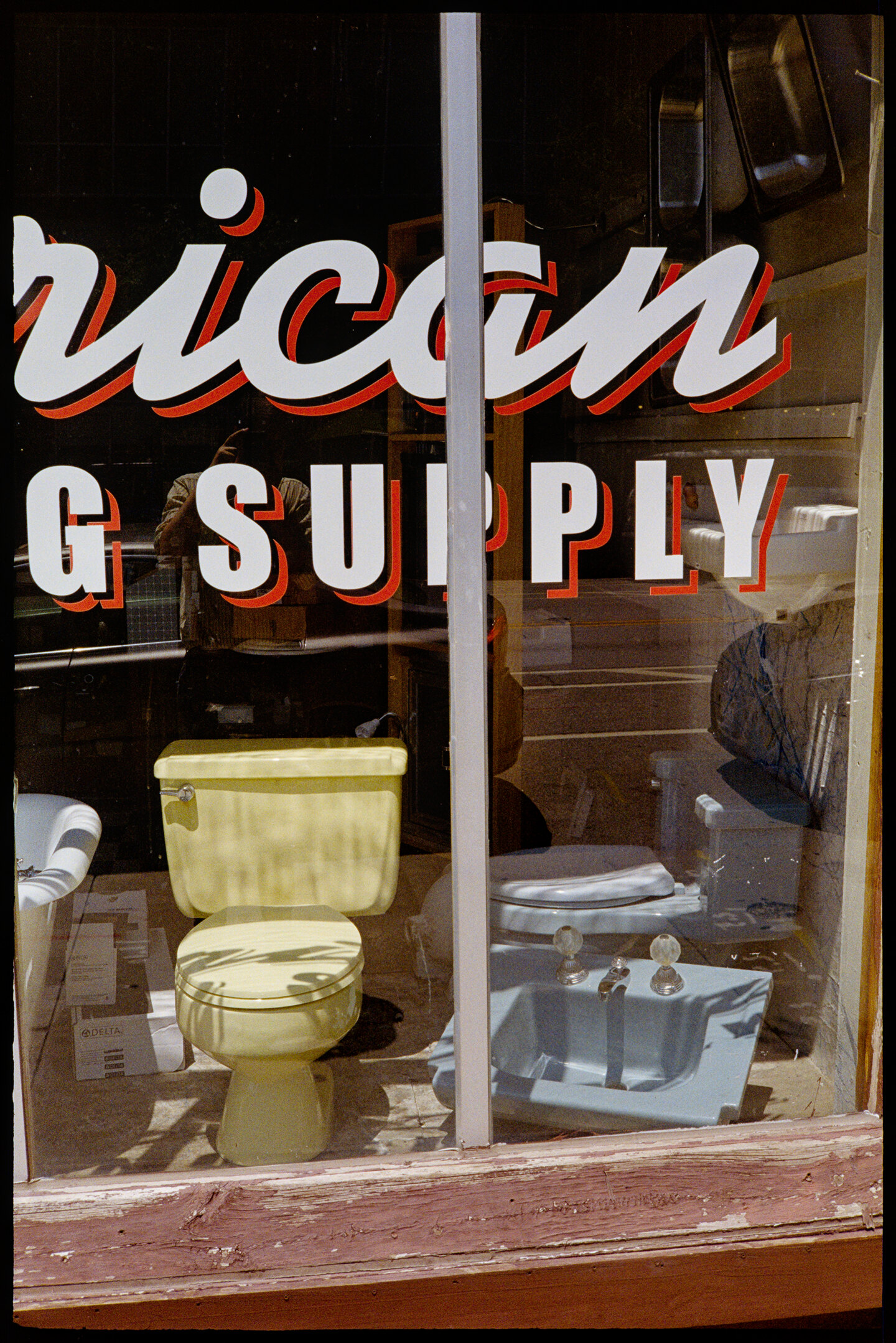 A toilet, sink, and tub in the front window of American Plumbing Supply shop in Des Moines