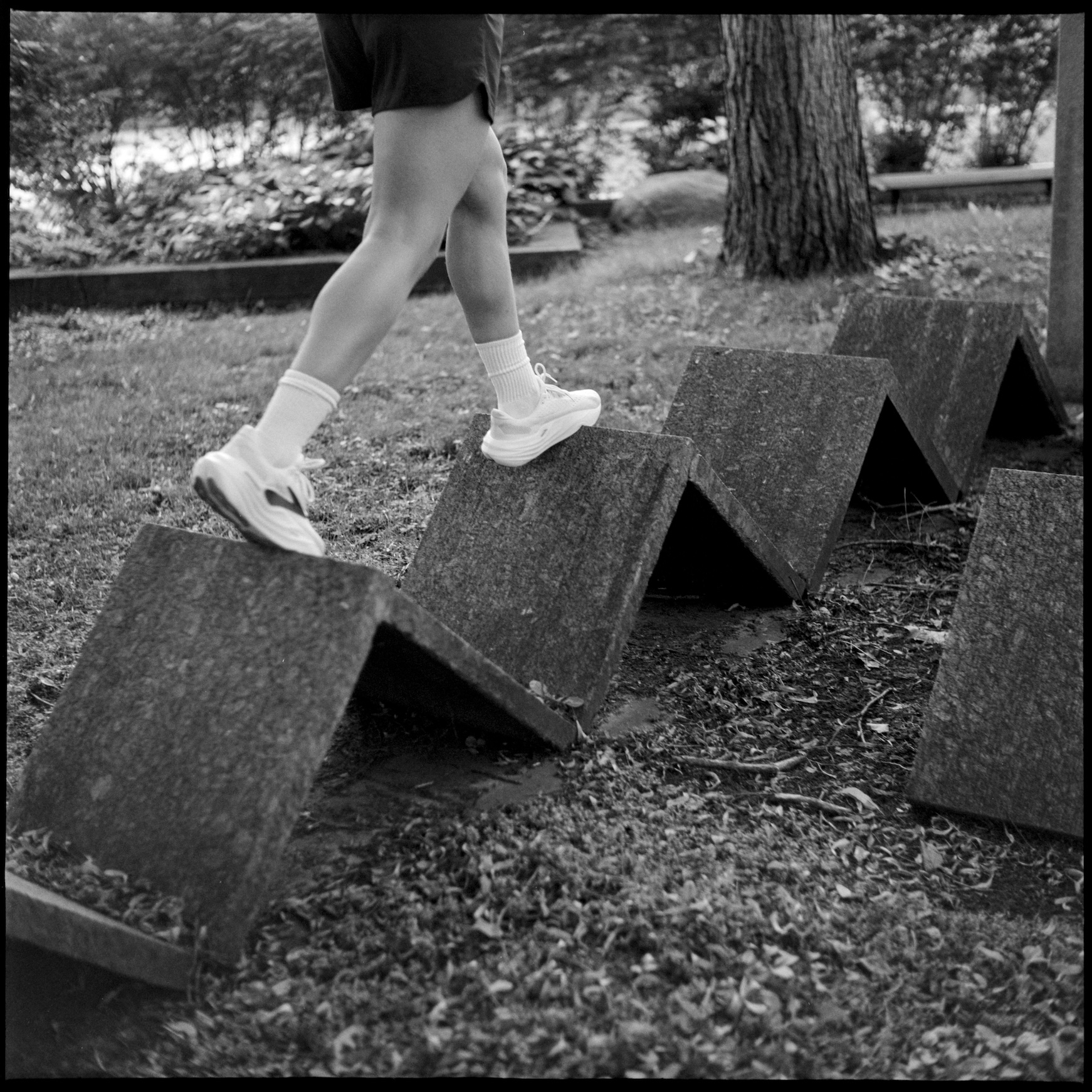 Kallie's legs walking over concrete sculpture in front of art building
