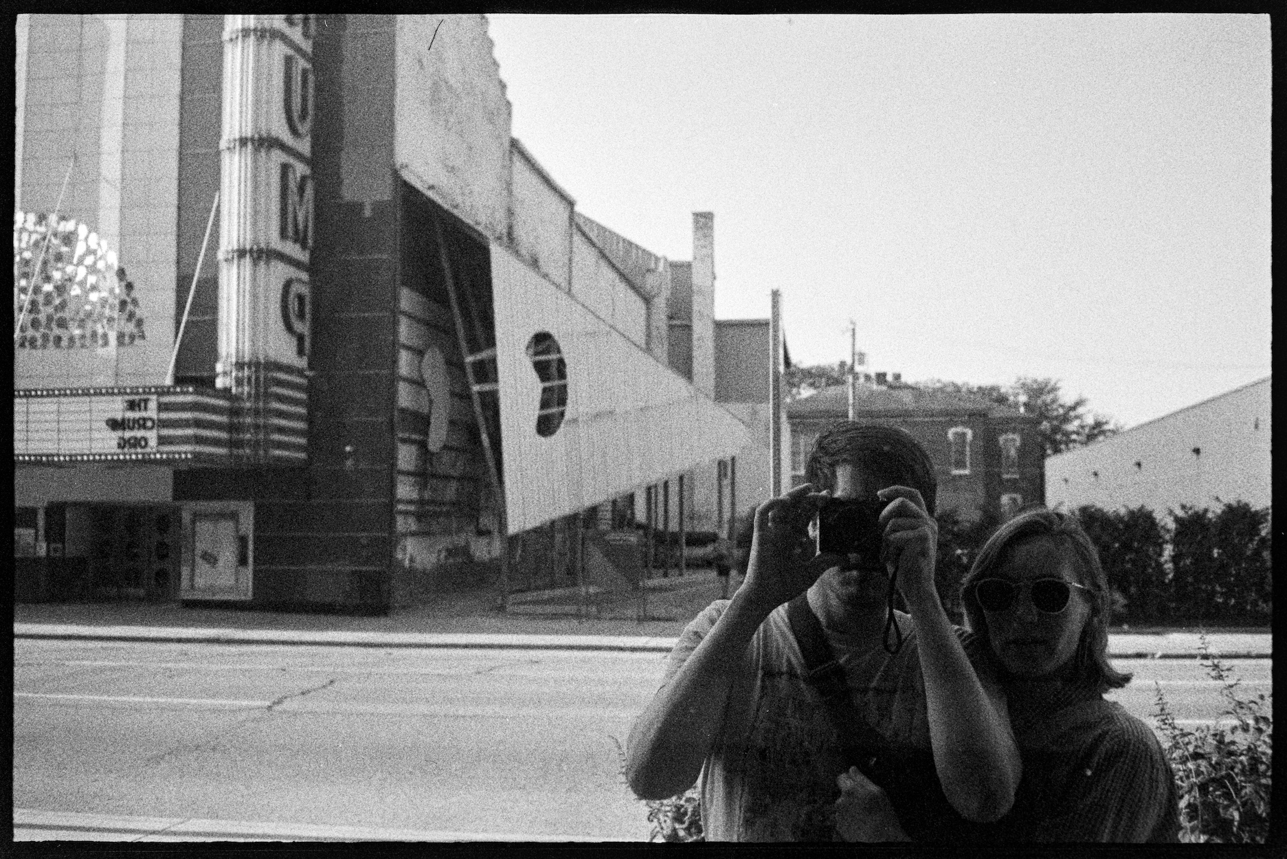 Jason and Kallie reflection in a window with the Crump theater behind them