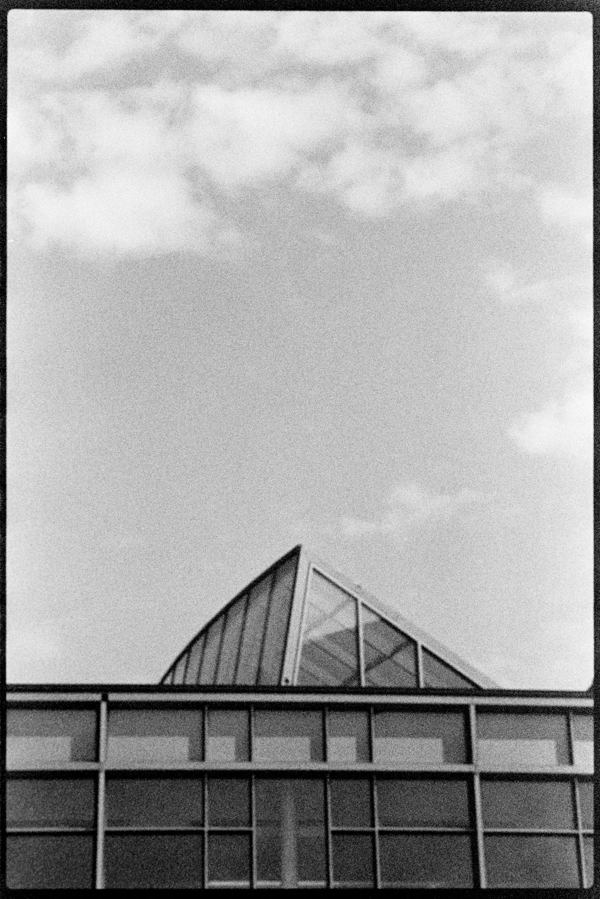 Glass roof of building and cloudy sky above it