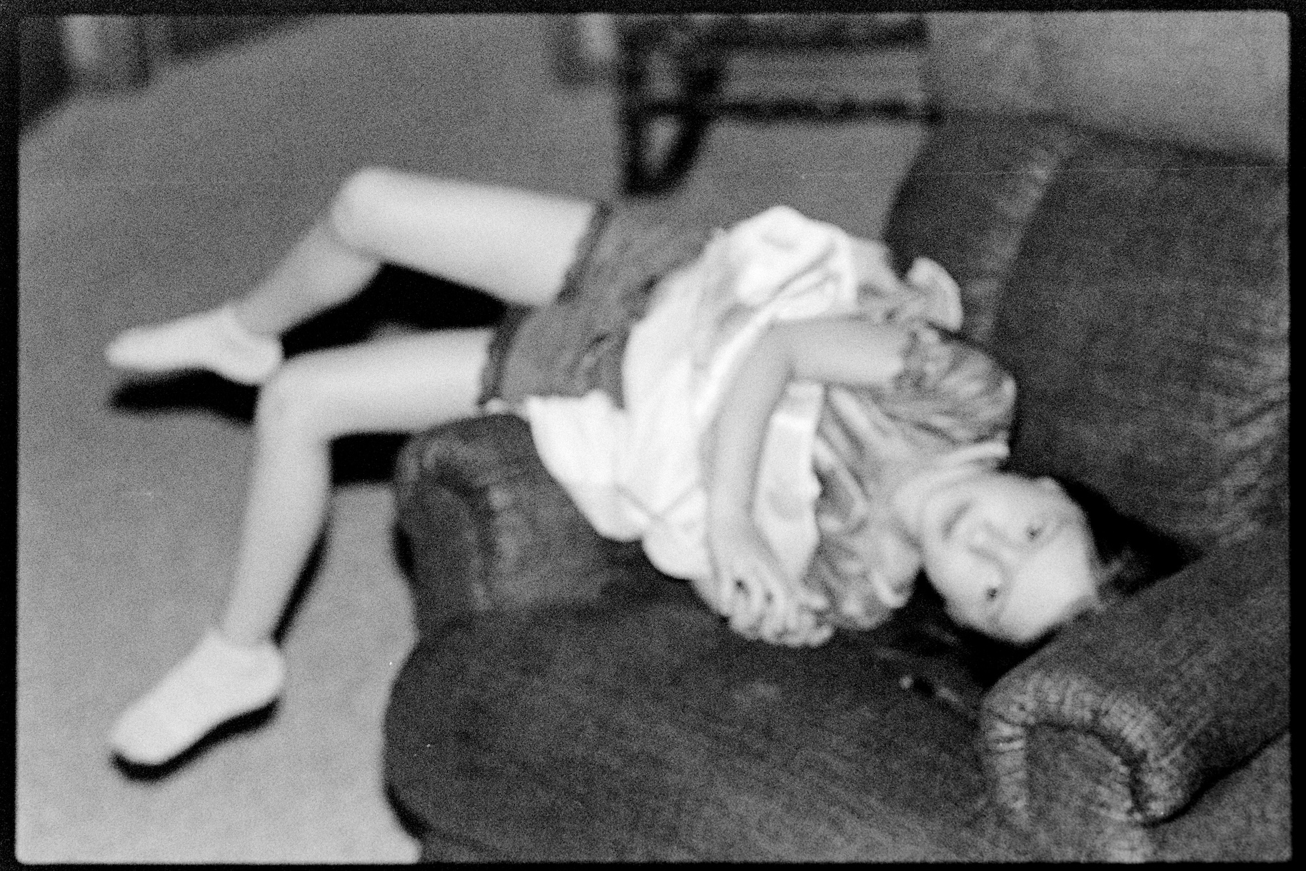 A child laying funnily across an armchair