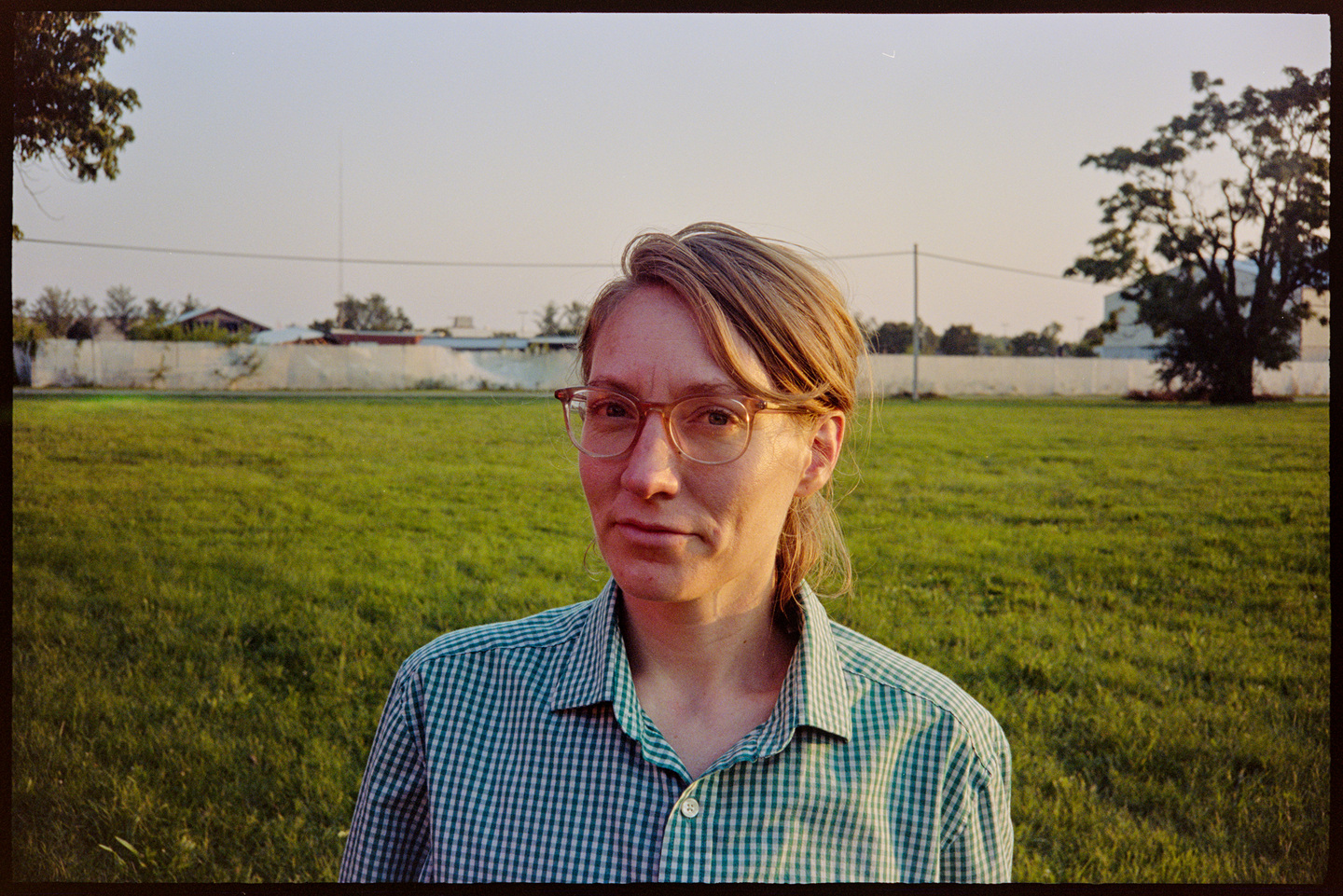 Kallie in the foreground with a green field in the background in the evening sun