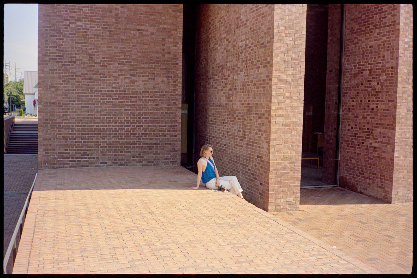Kallie sitting on the terrance in front of the public library. It's very sunny, so she's sitting in a shadow.