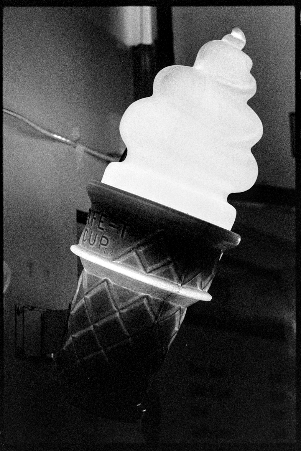 A light up soft serve cone on the side of a soft serve truck at the fair at night