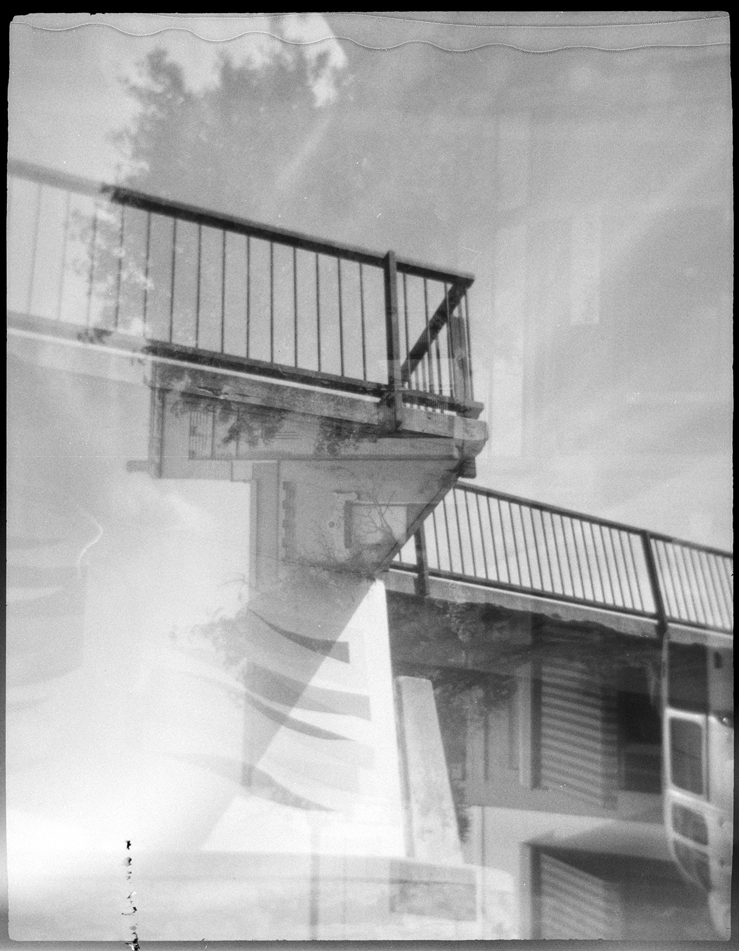 A bridge of a river overlaid with an accidental second exposure of a building