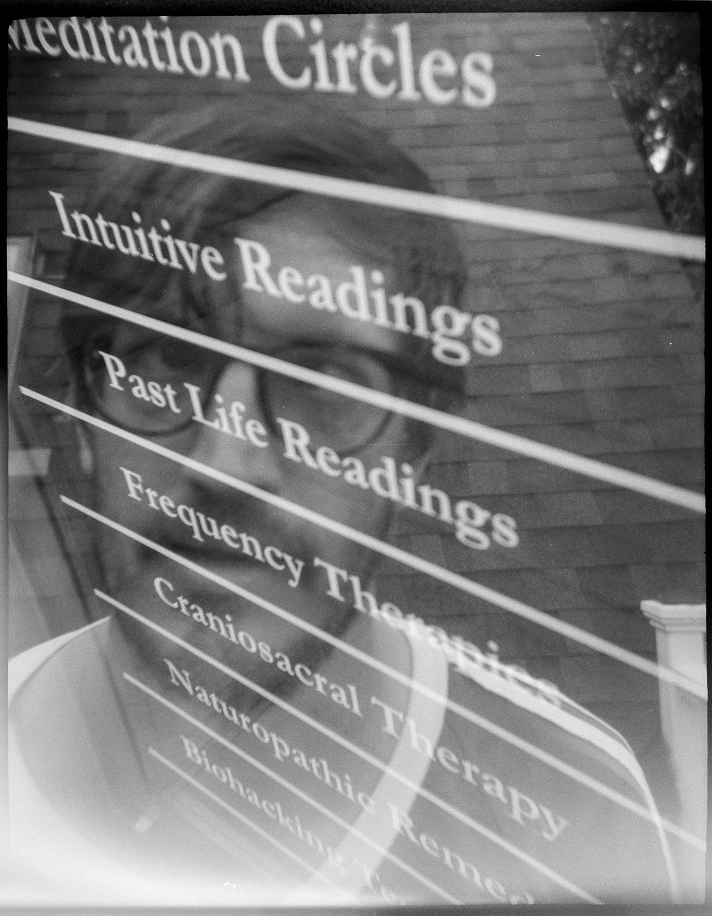 A multiple exposure of a sign advertising intuitive nad past life readings overlaid with a selfie shot of my face