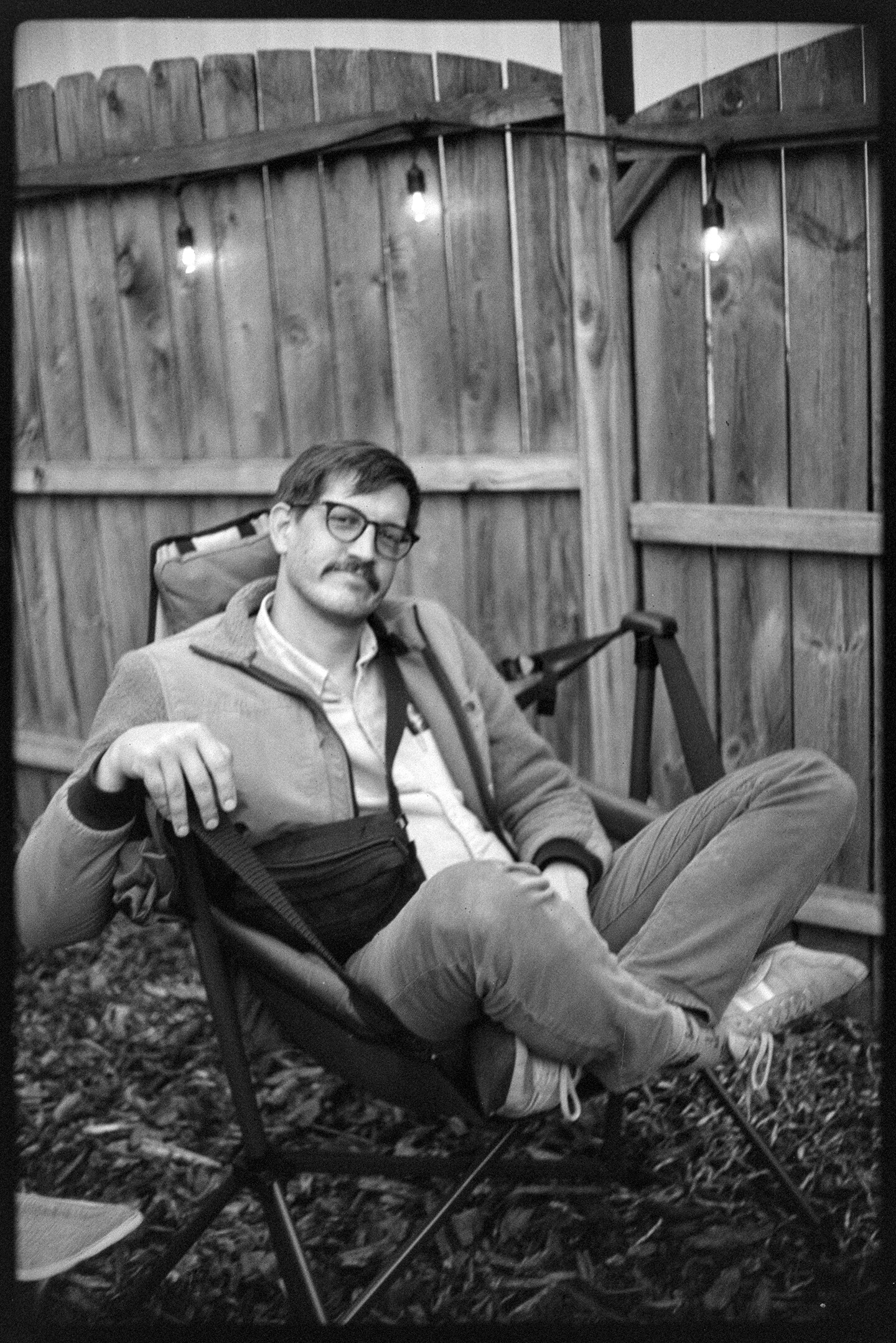 The author sitting cross-legged in a camping chair in front of a wooden fence