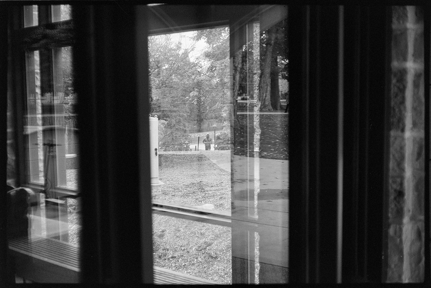 A young man walking up a hill shot through multiple windows of a building