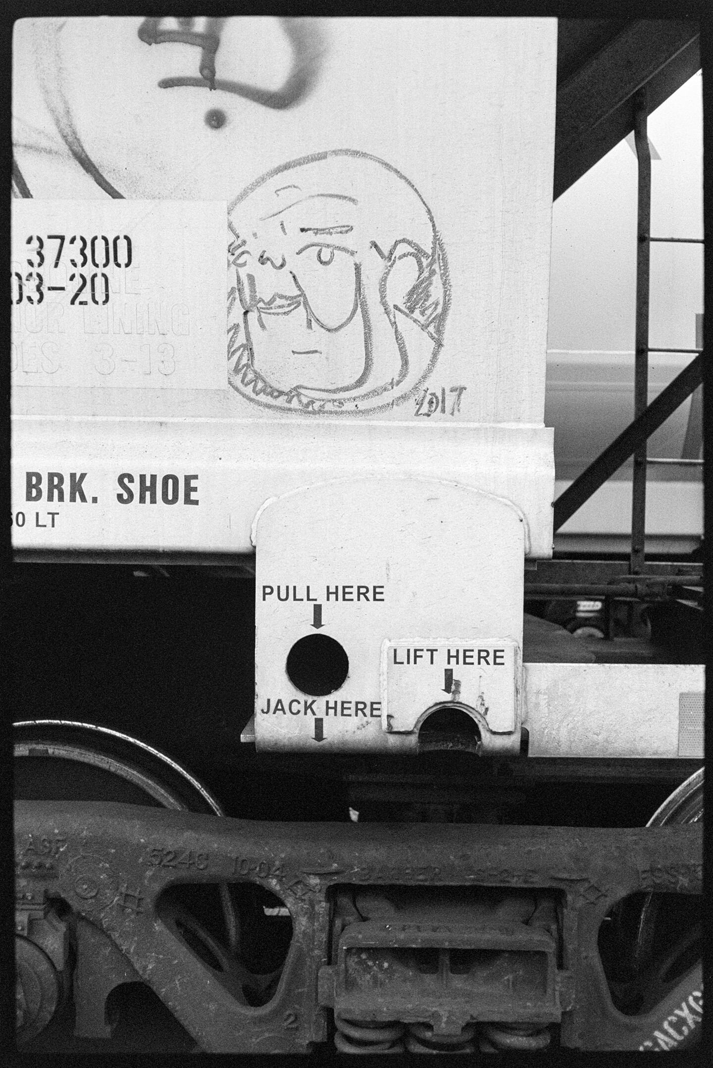 A freight train car with graffiti including a portrait of a man's face