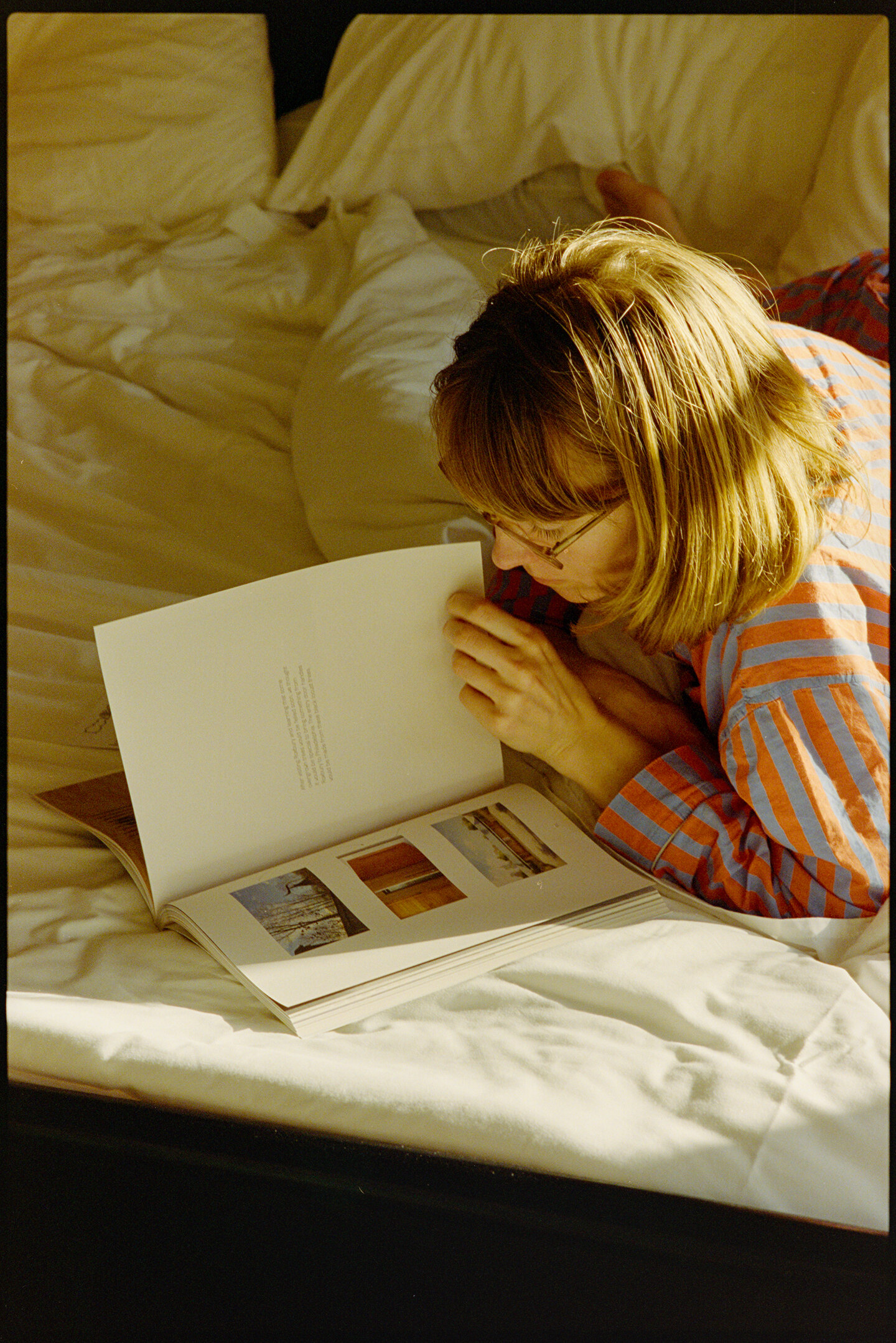 Kallie reading a book in bed at the Yowie hotel in the morning sunlight