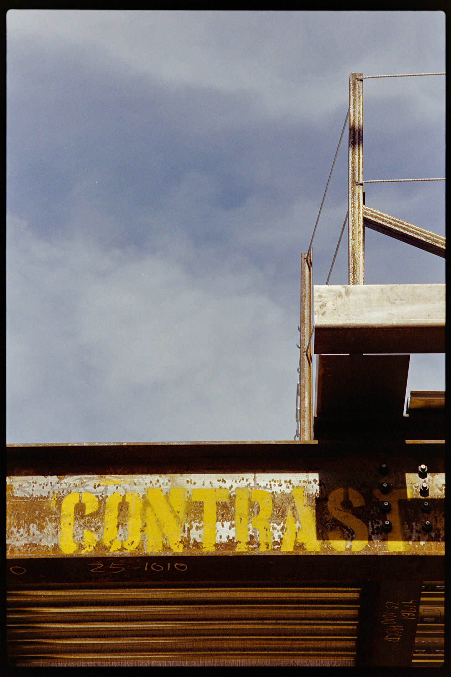 A steel beam at a construction site with the word CONTRAST stenciled on it and with the blue sky in the background