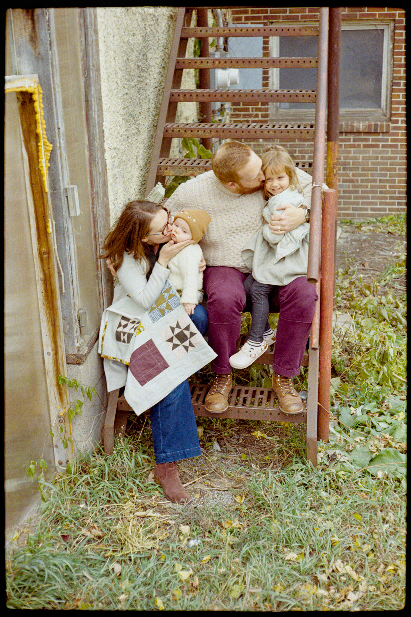 Courtney and James and their kids sitting in a stairwell behind the Oak Center