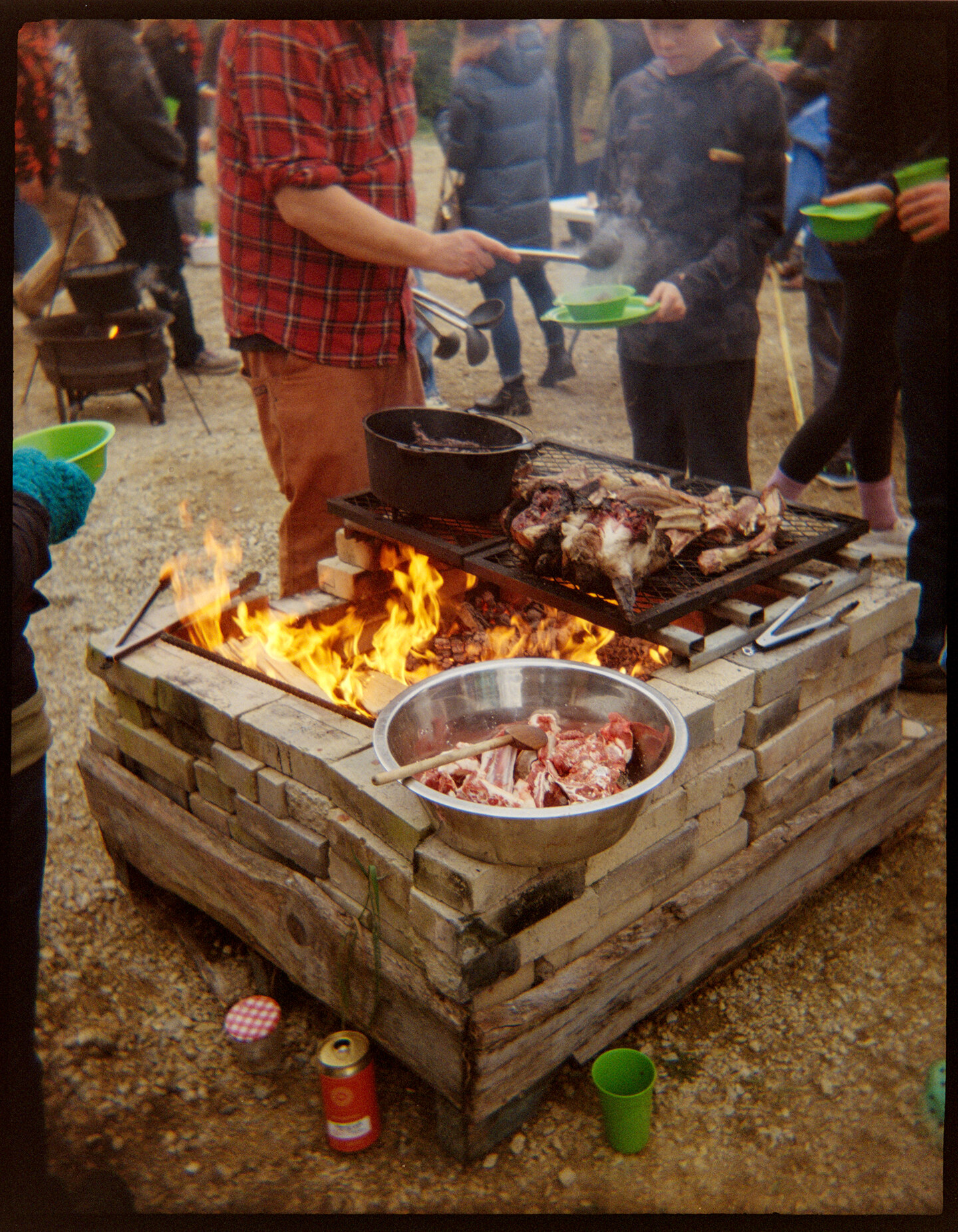 People standing around a fire where lamp is being grilled