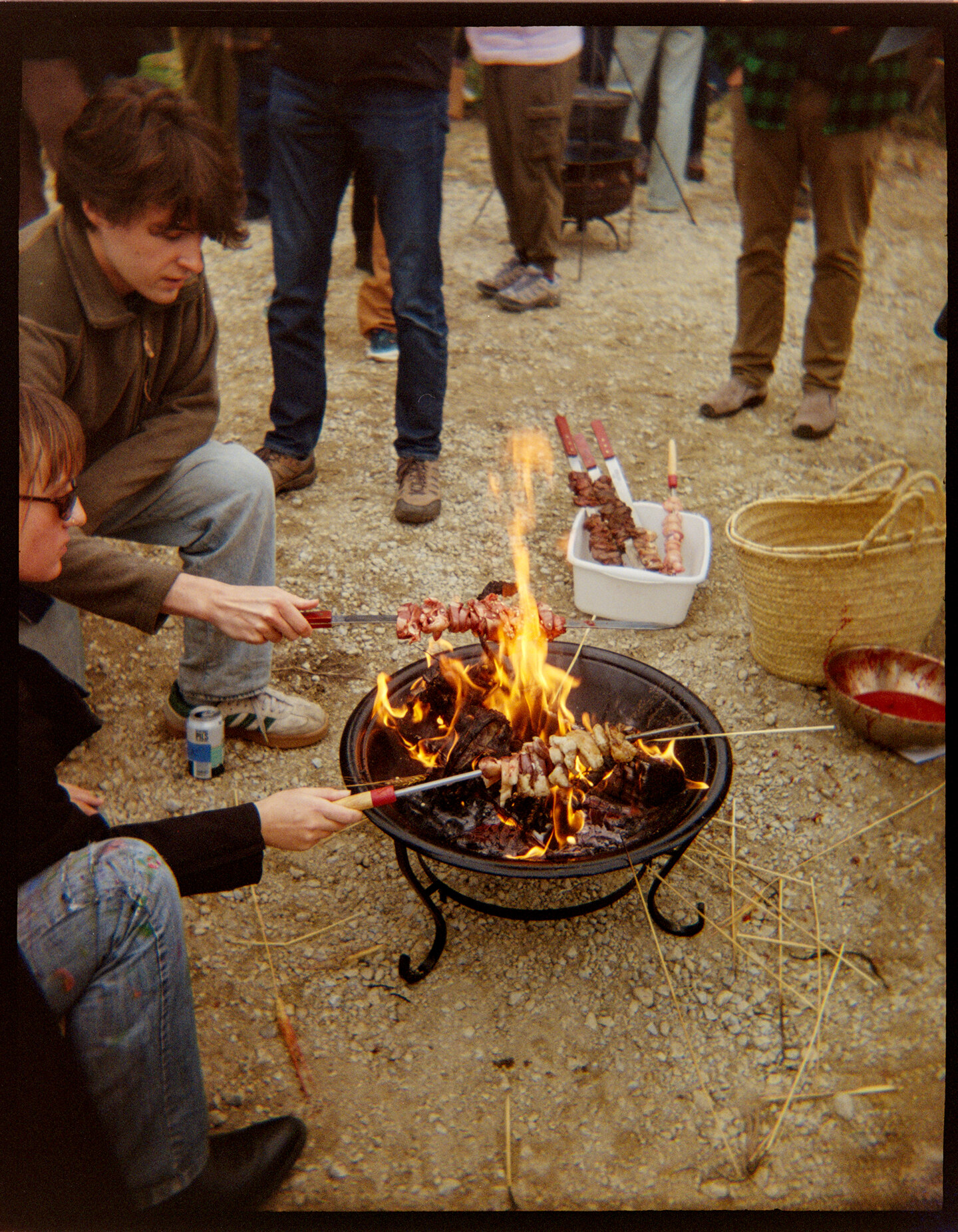 Two people grilling lamp meat on skewers over a fire