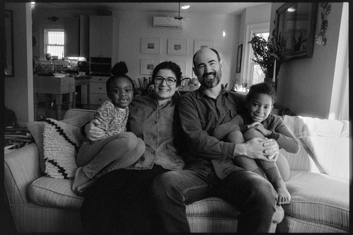 Family photo of Matt and Rachel with their kids Gio and Sakhmet sitting on the couch