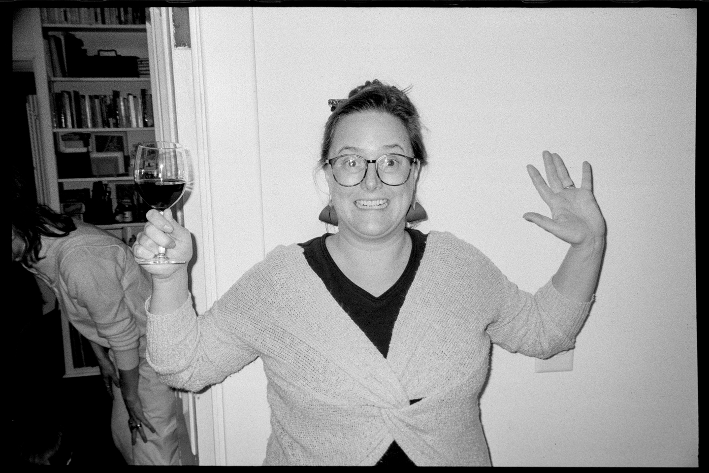 Sinda holds up her hands with a wine glass in her hand during the solstice party