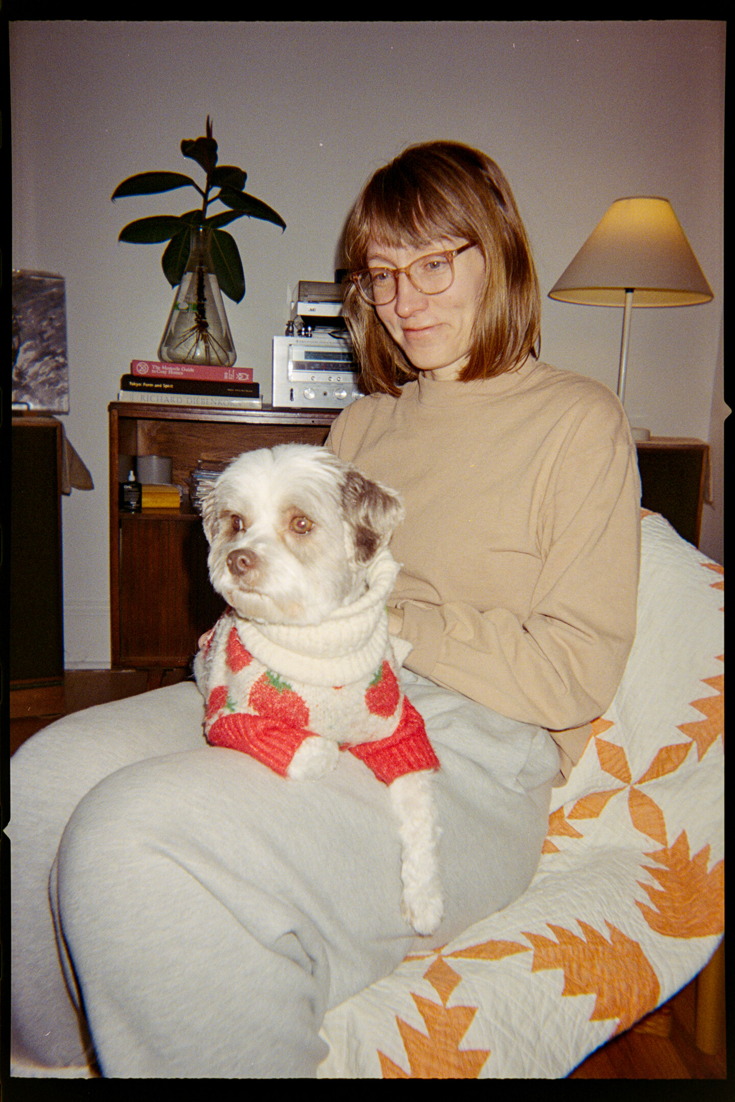 A woman sitting in a chair with her small white dog sitting in her lap.