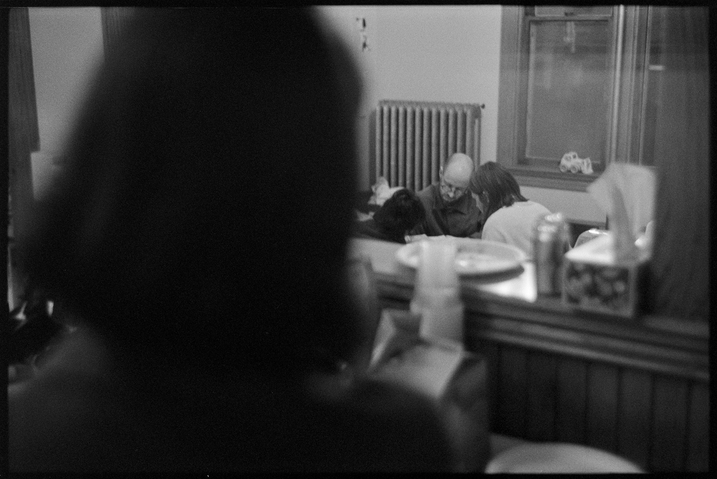 The back of a woman's head in the foreground and a group of people playing a game at a party in the background