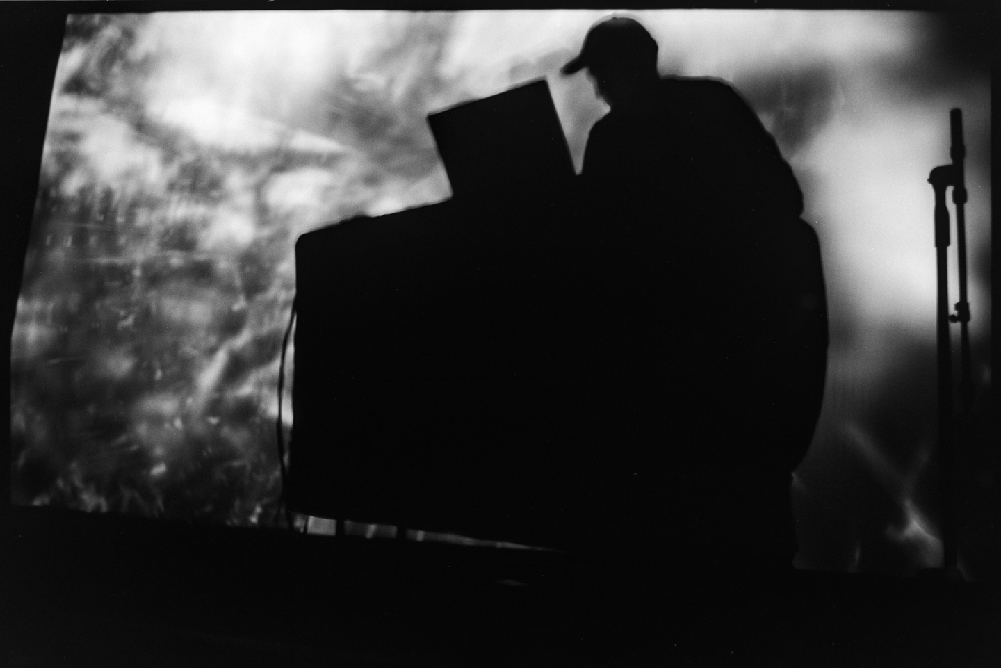Tom Hall performing on a laptop in front of a large projection of digital animation at the Algorithmic Art Assembly v.3